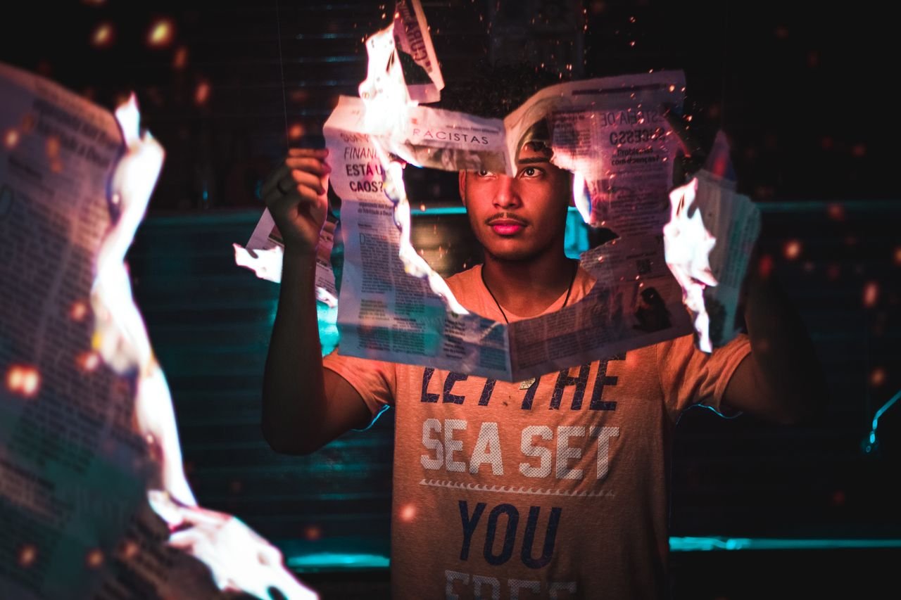 Mastering the First Impression: Your intriguing post title goes here A young man holding a burning newspaper, creating a dramatic and intense atmosphere.