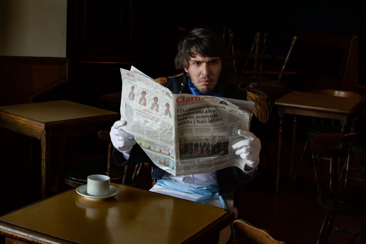 Services A man in a historical uniform reads a Clarin newspaper in a Buenos Aires café.